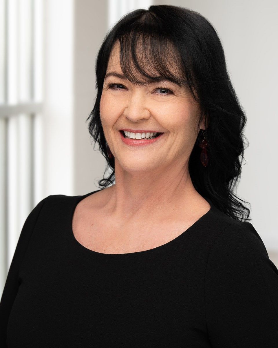 A woman in a black shirt is smiling for the camera.