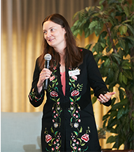 A woman in a black coat is holding a microphone.