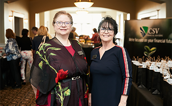 Two women are standing next to each other in a hallway.