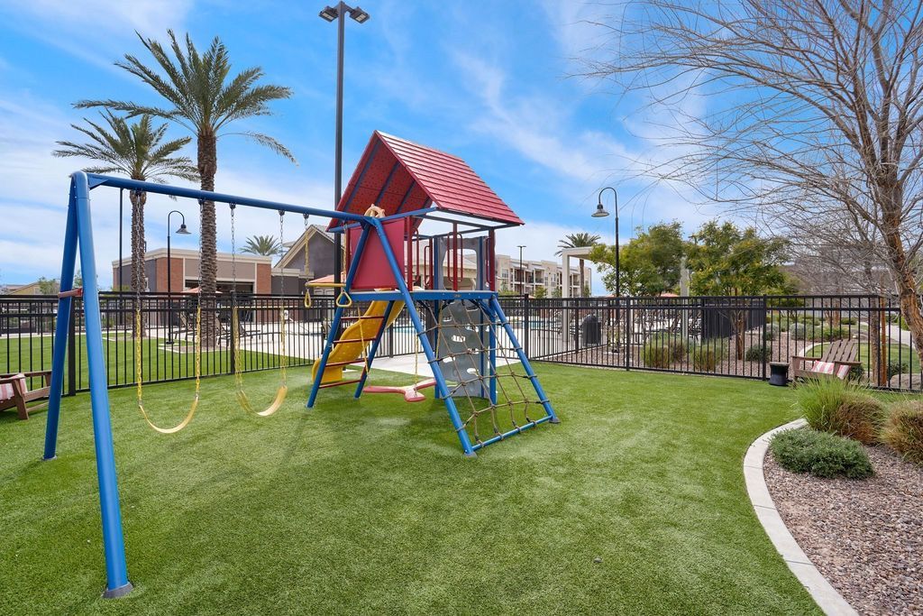 Playground with swings and a climbing structure inside a fenced apartment complex.