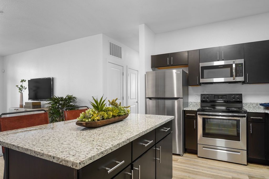 Kitchen in an apartment with stainless steel appliances and a granite island.
