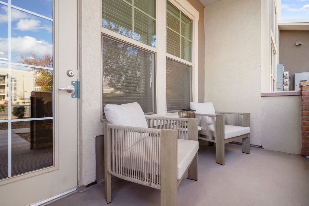 Exterior apartment balcony with two cushioned chairs and a small table.
