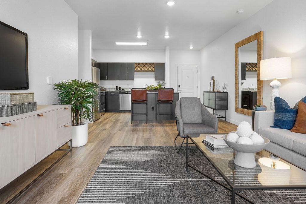 Open-concept living area with a kitchen island, seating, and a wall-mounted TV.