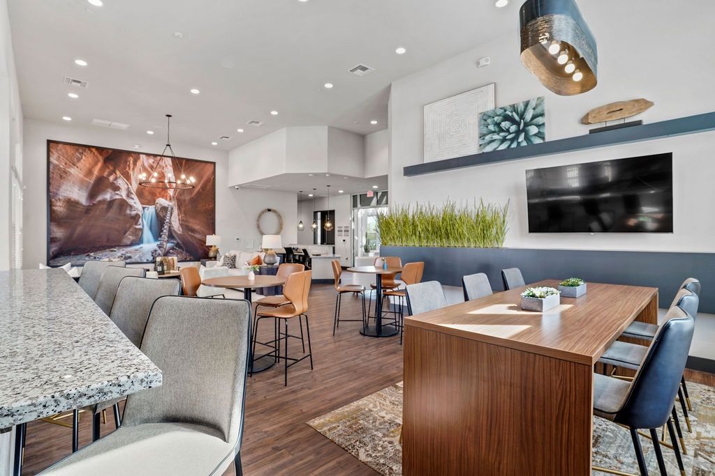 Bright communal lounge with modern seating, a large TV, and greenery.