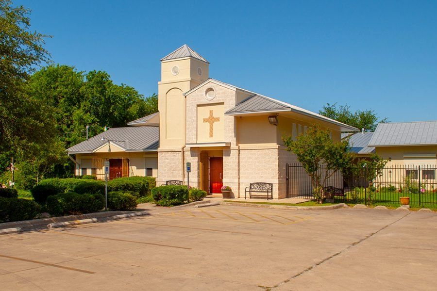 a church with a cross on the front of it and a parking lot in front of it .