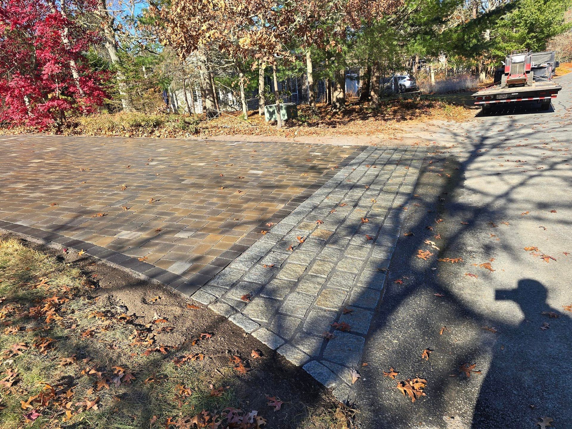 A car is parked in a driveway next to a brick walkway.