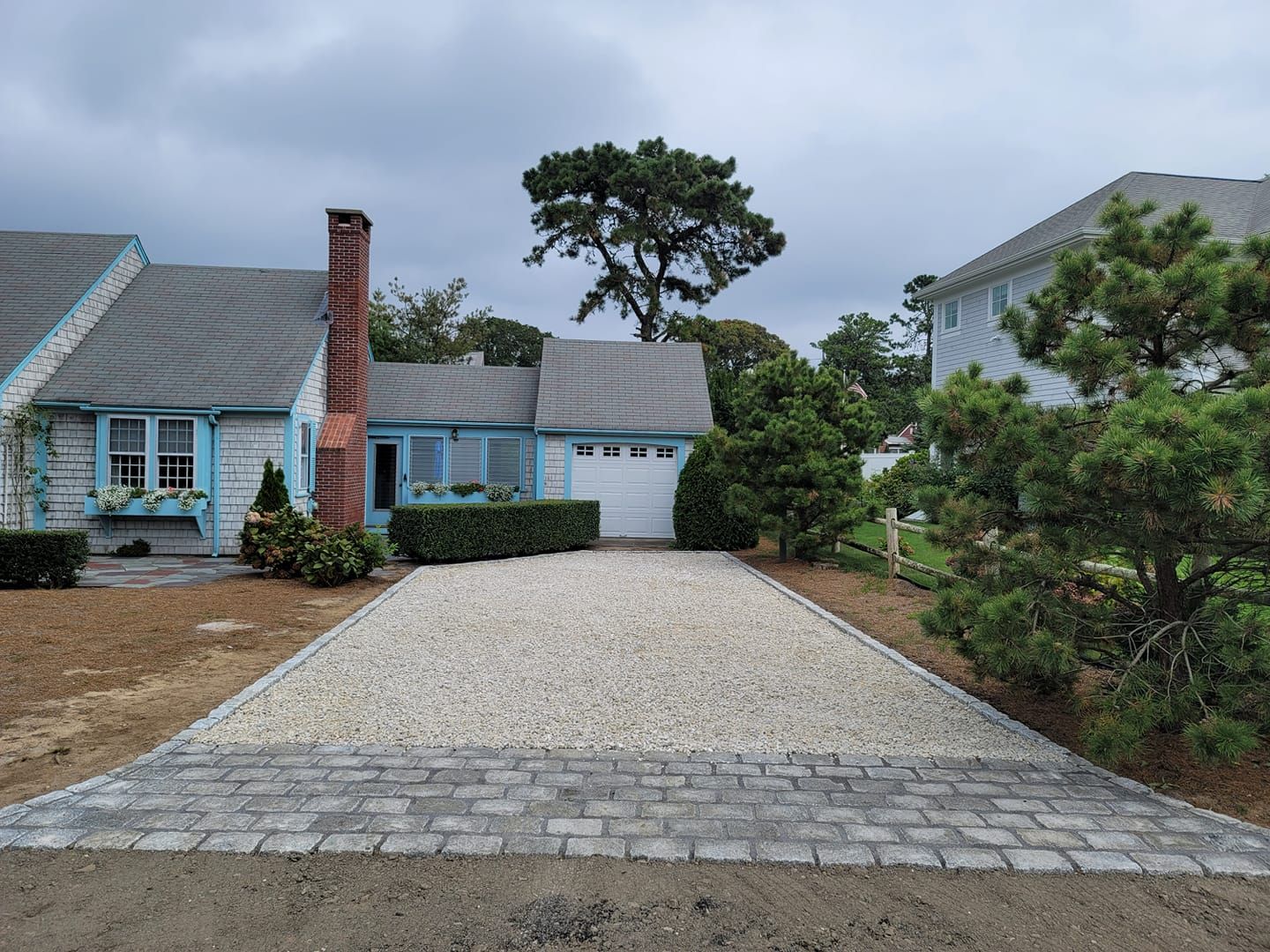 A blue house with a gravel driveway leading to it.