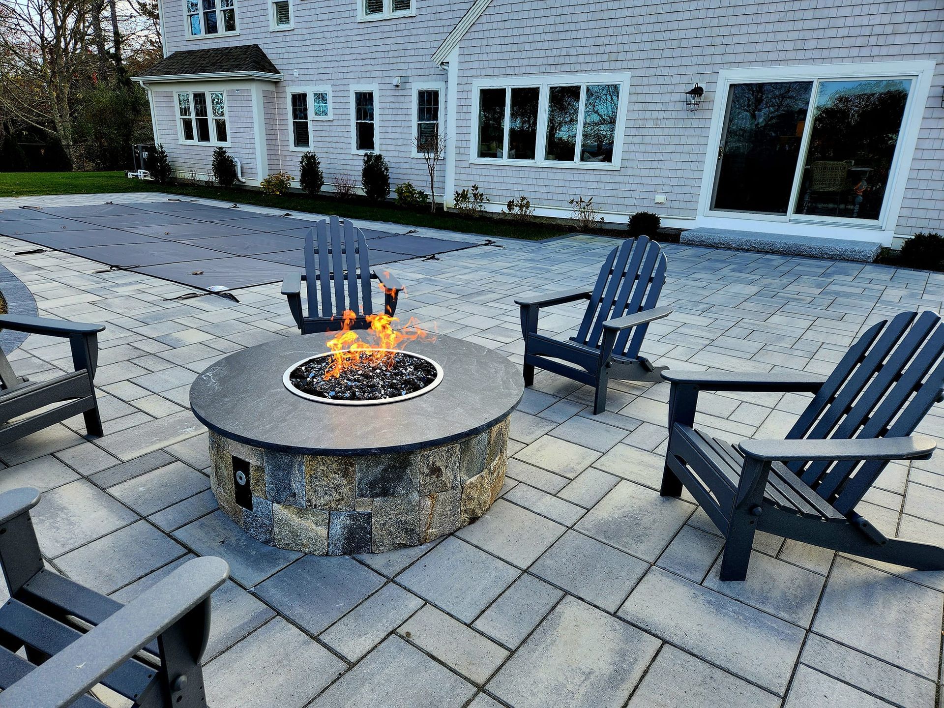 There is a fire pit on the patio with chairs around it.