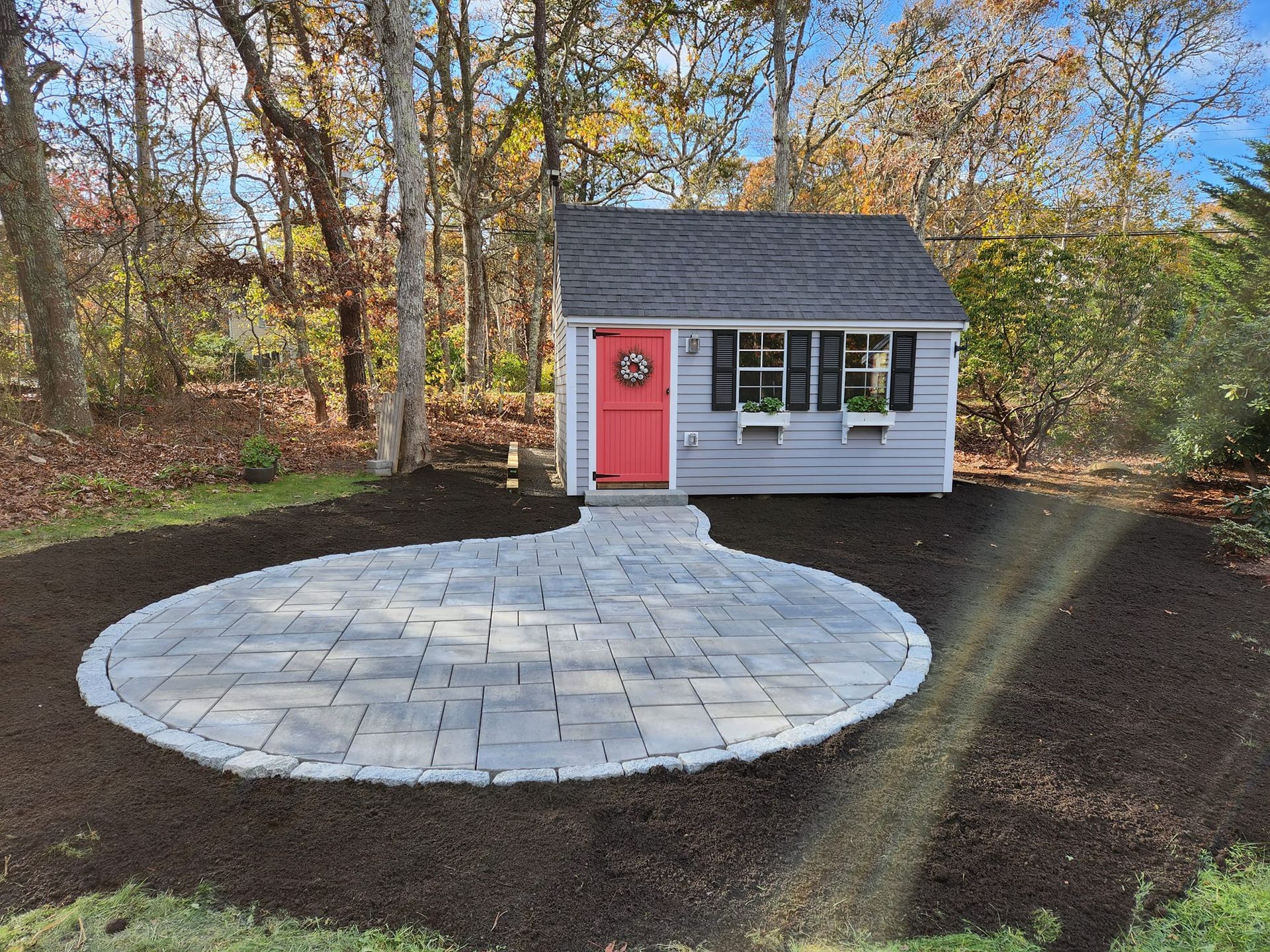 A small house with a red door and a patio in front of it.