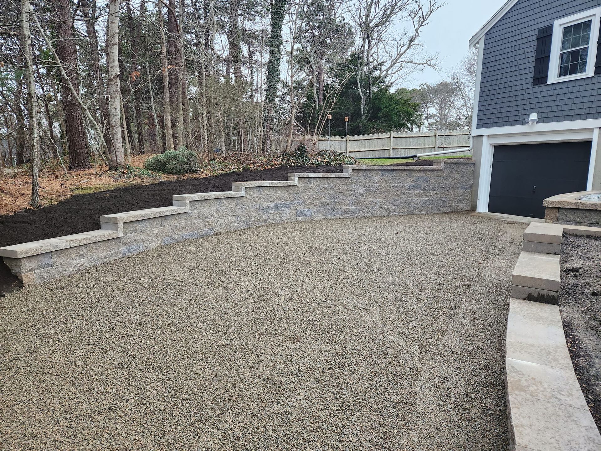 A gravel driveway with steps leading up to a garage next to a house.