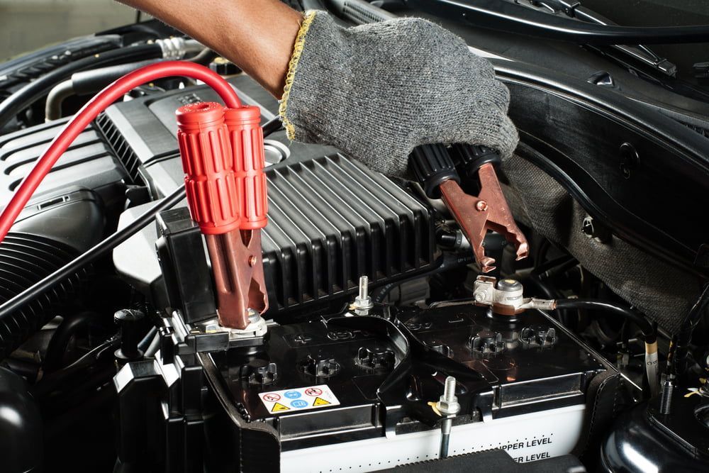 A Person Uses Jumper Cables to Connect to a Car Battery — Norm Beatty's Auto Electrical Service In Long Jetty, NSW