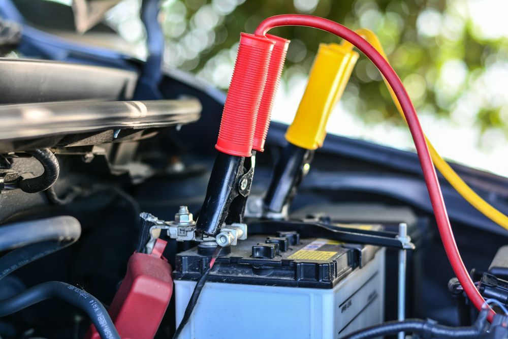 A Car Battery With Red and Yellow Jumper Cables Attached — Norm Beatty's Auto Electrical Service In Long Jetty, NSW