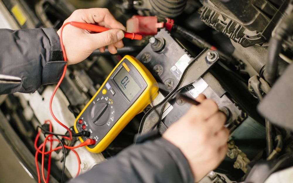 A Car Battery With a Yellow Multimeter — Norm Beatty's Auto Electrical Service In Long Jetty, NSW