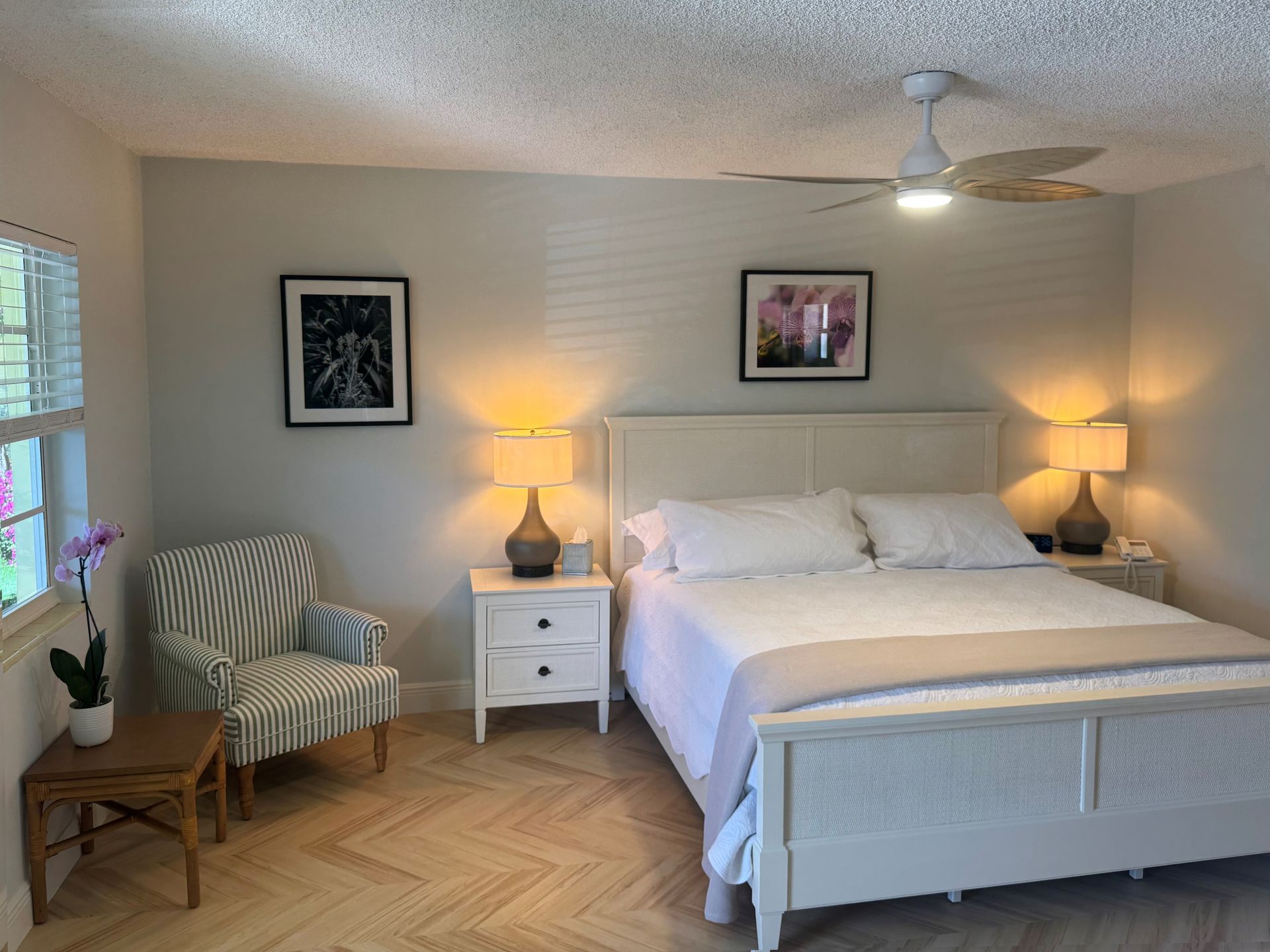 A bedroom with a white bed, pink walls, and a ceiling fan. A TV and a mirror are visible.