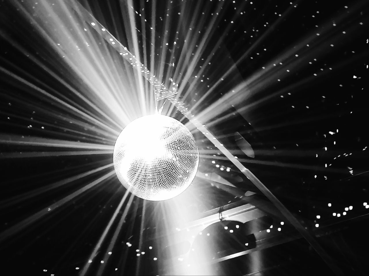 Una palla da discoteca che riflette la luce in tutte le direzioni, illuminando uno spazio buio.