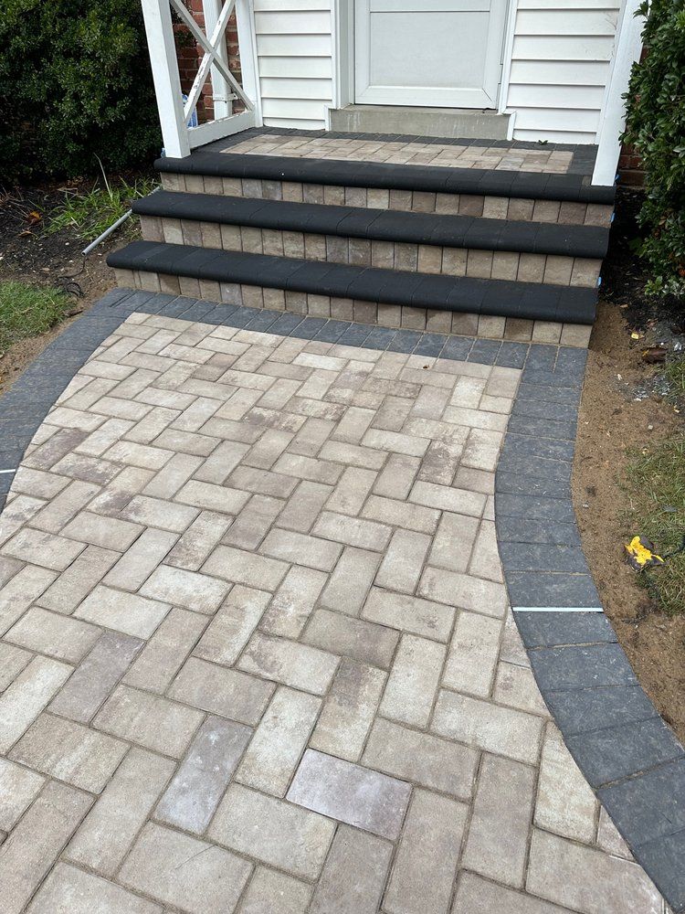 Brick pathway leading to steps and front door. Pathway and steps trimmed in gray.