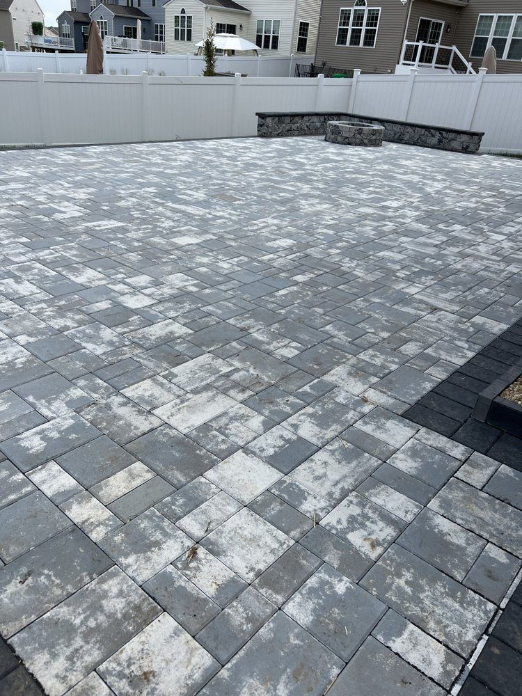 Gray brick patio with white fencing and stone fire pit.