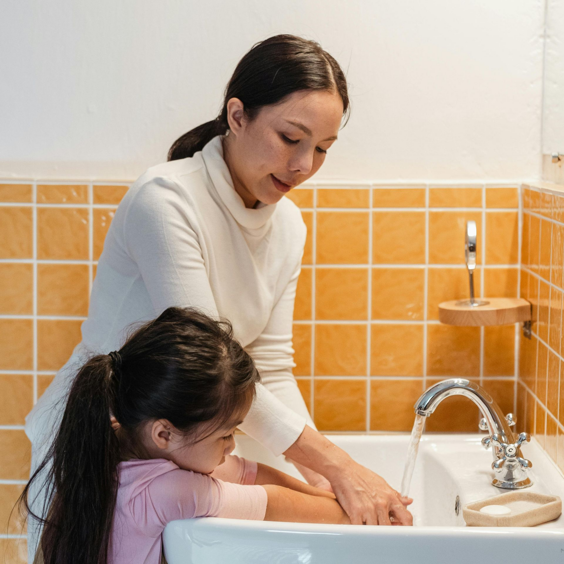 A parent and child wash their hands