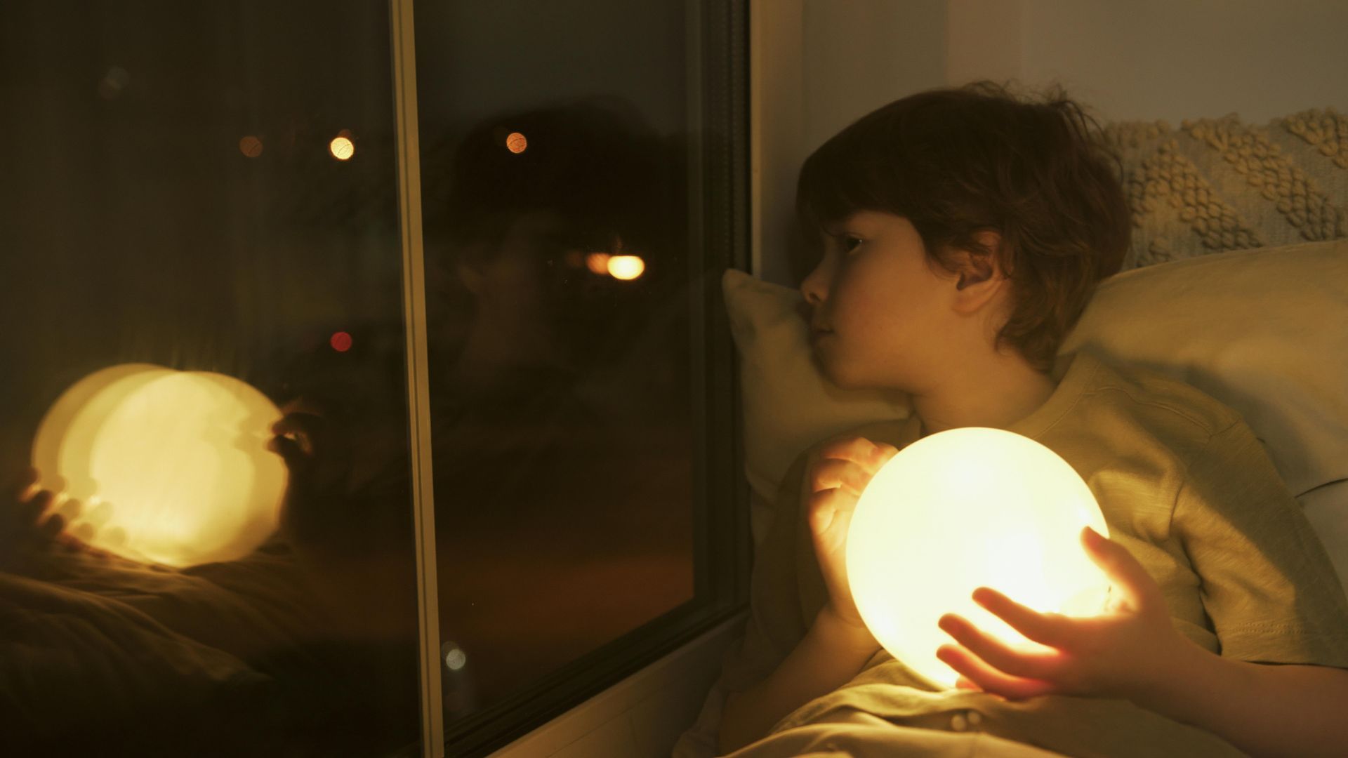 A boy looking out window at night