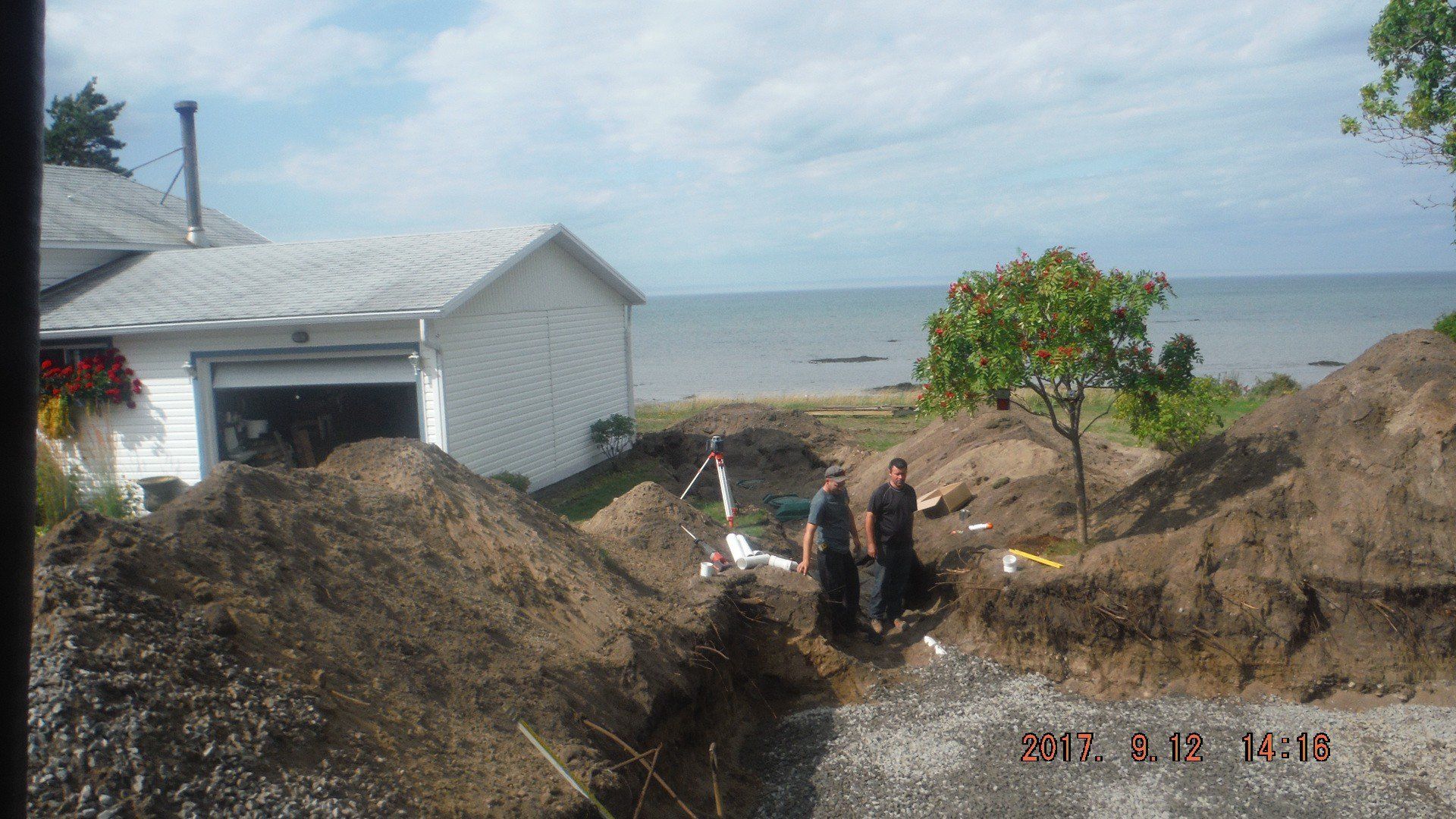 2 ouvriers qui regardent une installation septique en bordure d'un lac