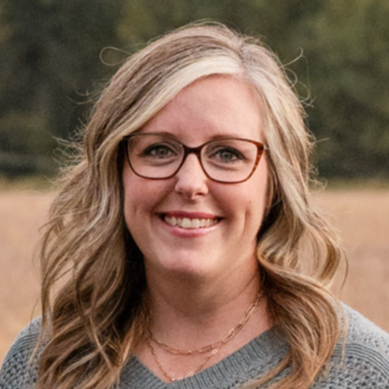 A woman wearing glasses and a scarf is smiling for the camera.
