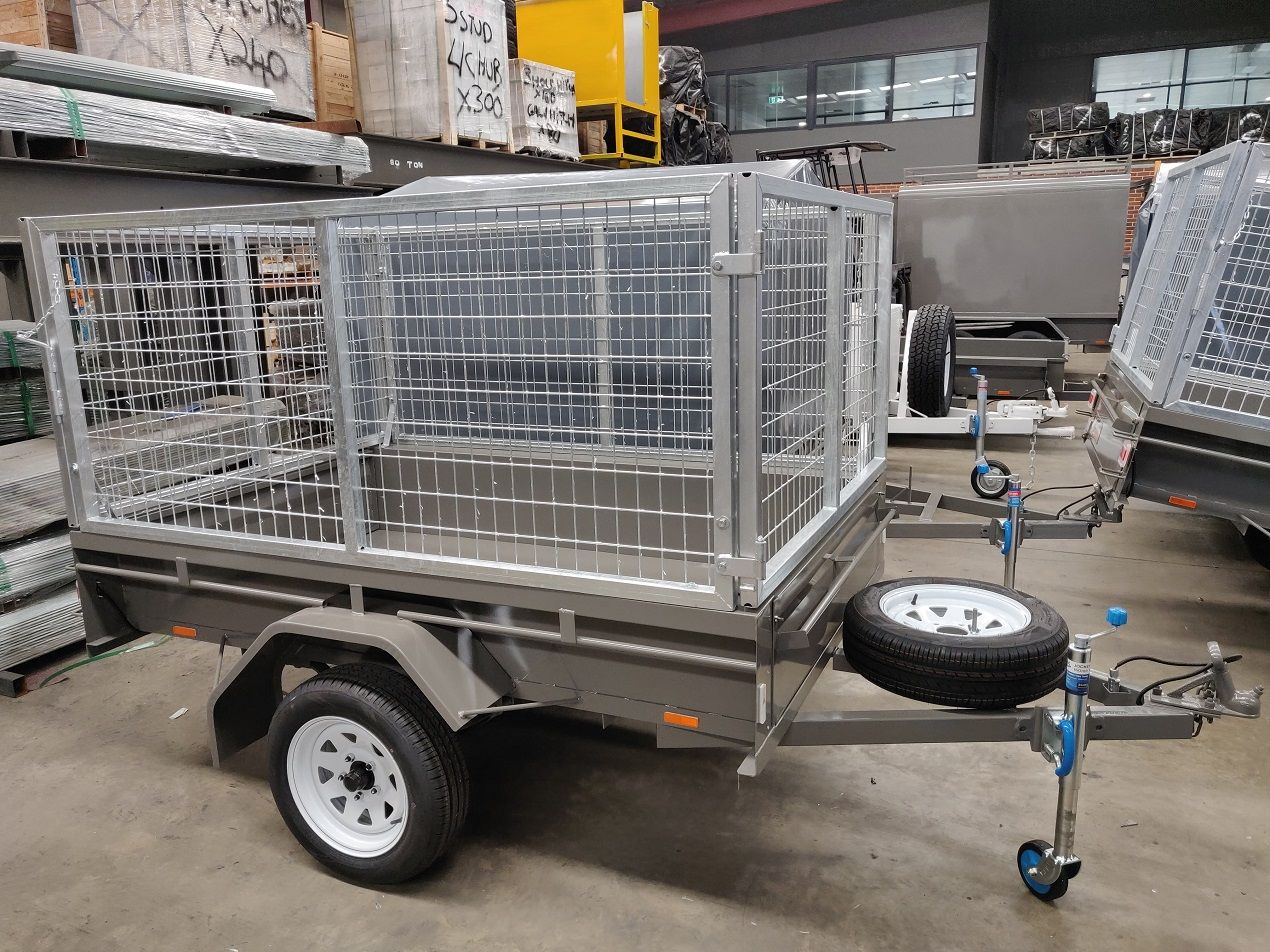 A single axel cage trailer with a cage on top is parked in a warehouse.