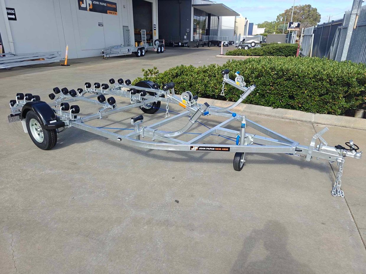 A boat trailer is parked on the side of the road in front of a building.
