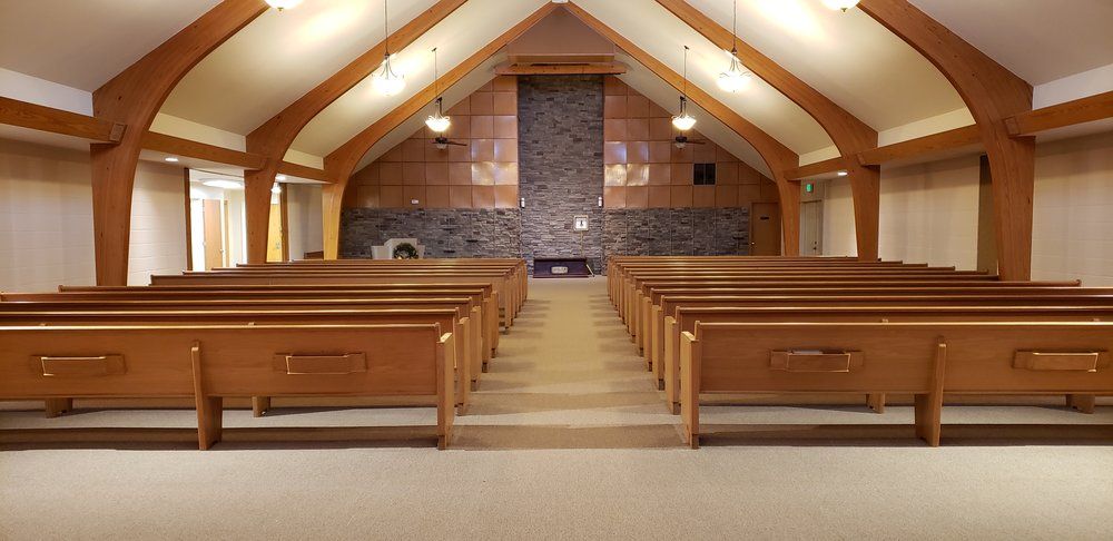 A church with rows of wooden benches and a fireplace.