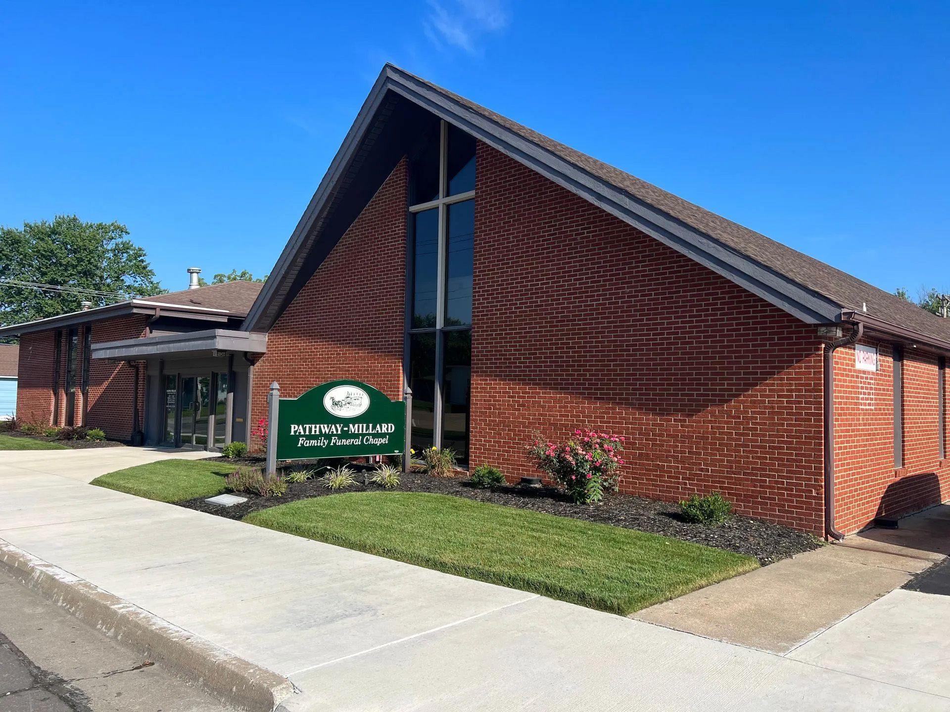 A large brick building with a green sign in front of it.