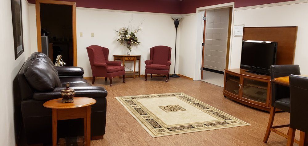 A living room with a couch , chairs , table and television.