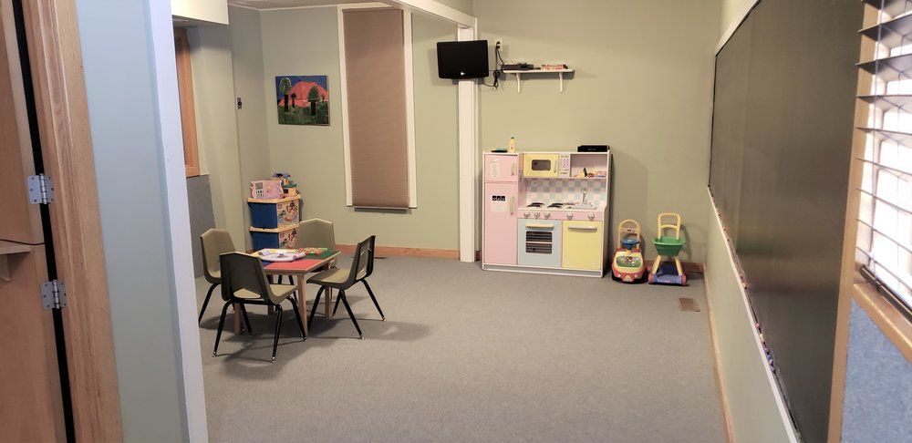 A room with a table and chairs in it and a blackboard.