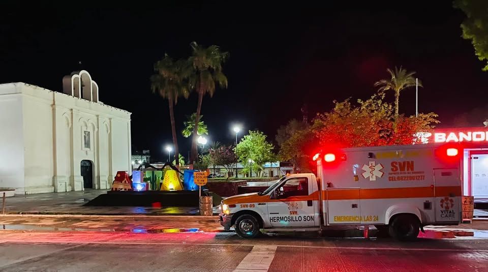 Una ambulancia está estacionada frente a una iglesia por la noche.