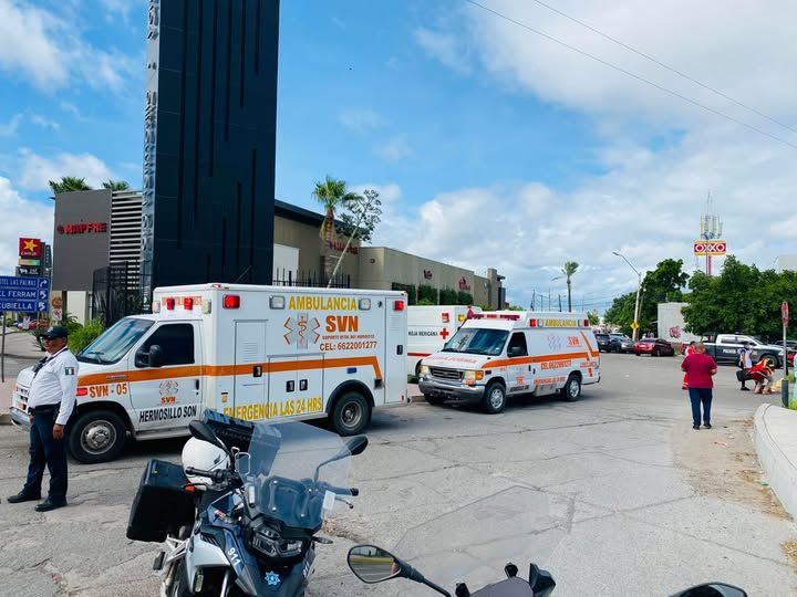 Una motocicleta está estacionada frente a una ambulancia en un estacionamiento.