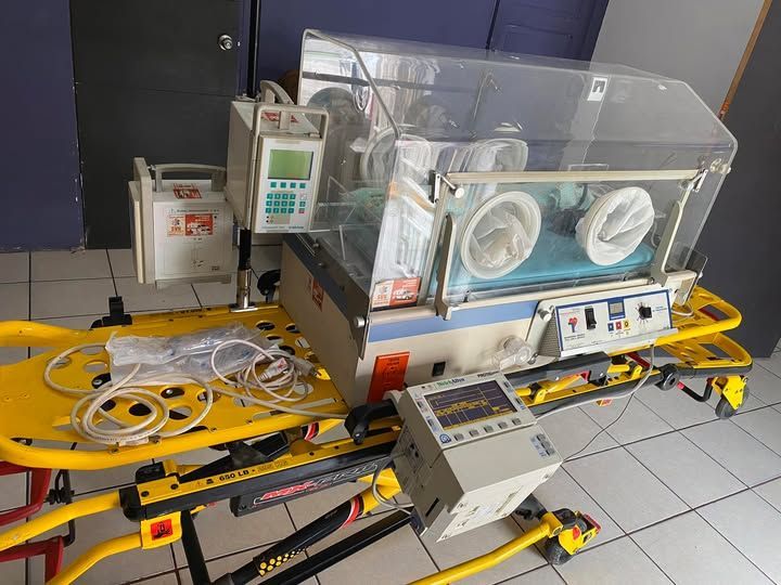 Una incubadora de bebés está colocada encima de una camilla amarilla.