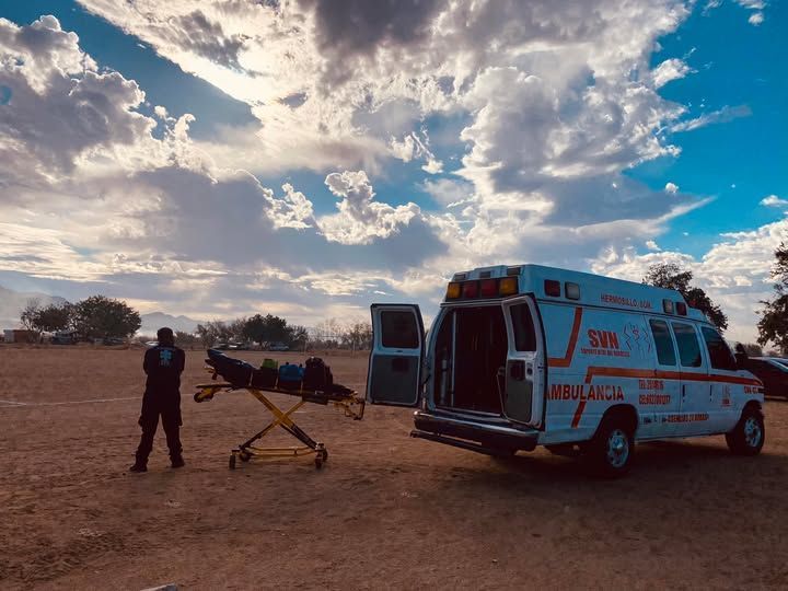 Un hombre está de pie junto a una ambulancia con una camilla adjunta.