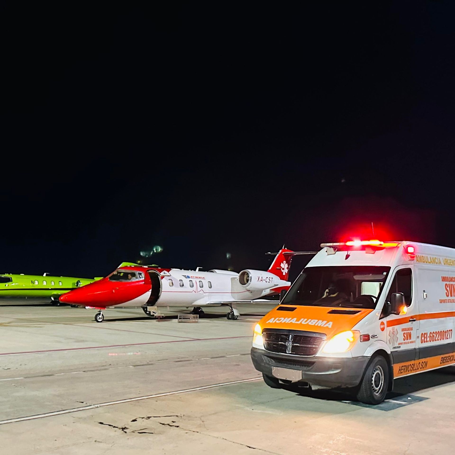 Una ambulancia está estacionada en una pista junto a un avión.