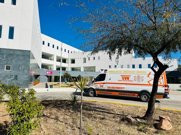 Una ambulancia está estacionada frente a un edificio de hospital.