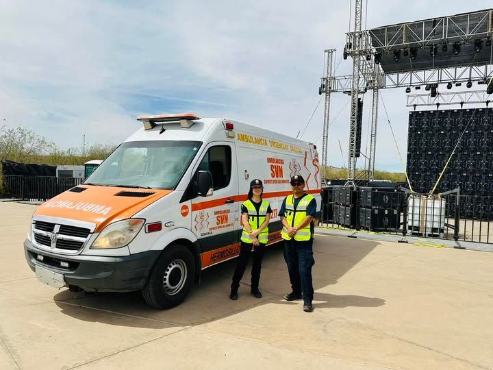 Dos hombres están de pie junto a una ambulancia en un estacionamiento.