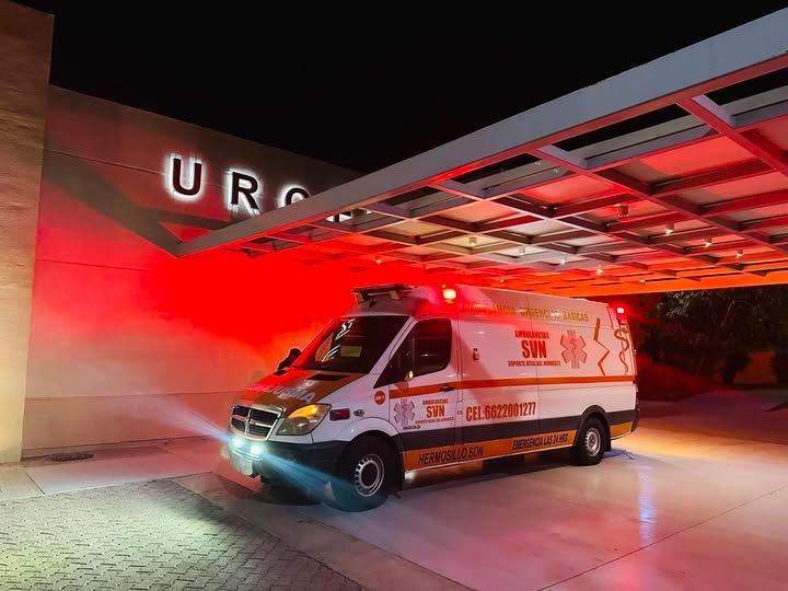 Una ambulancia está estacionada frente a un hospital por la noche.