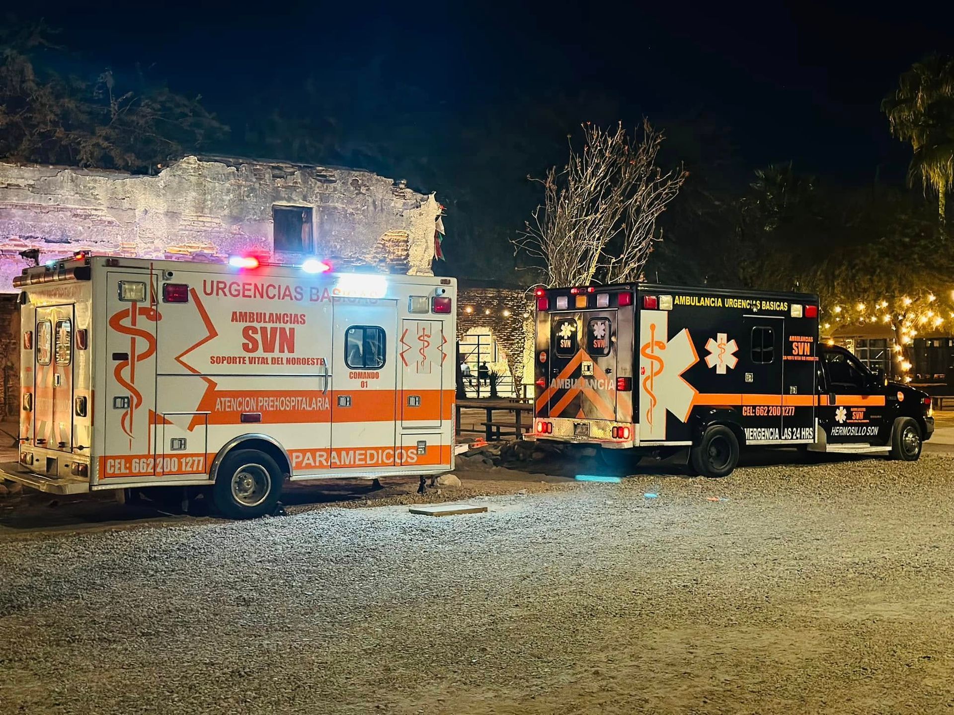 Dos ambulancias están estacionadas una al lado de la otra en un estacionamiento por la noche.