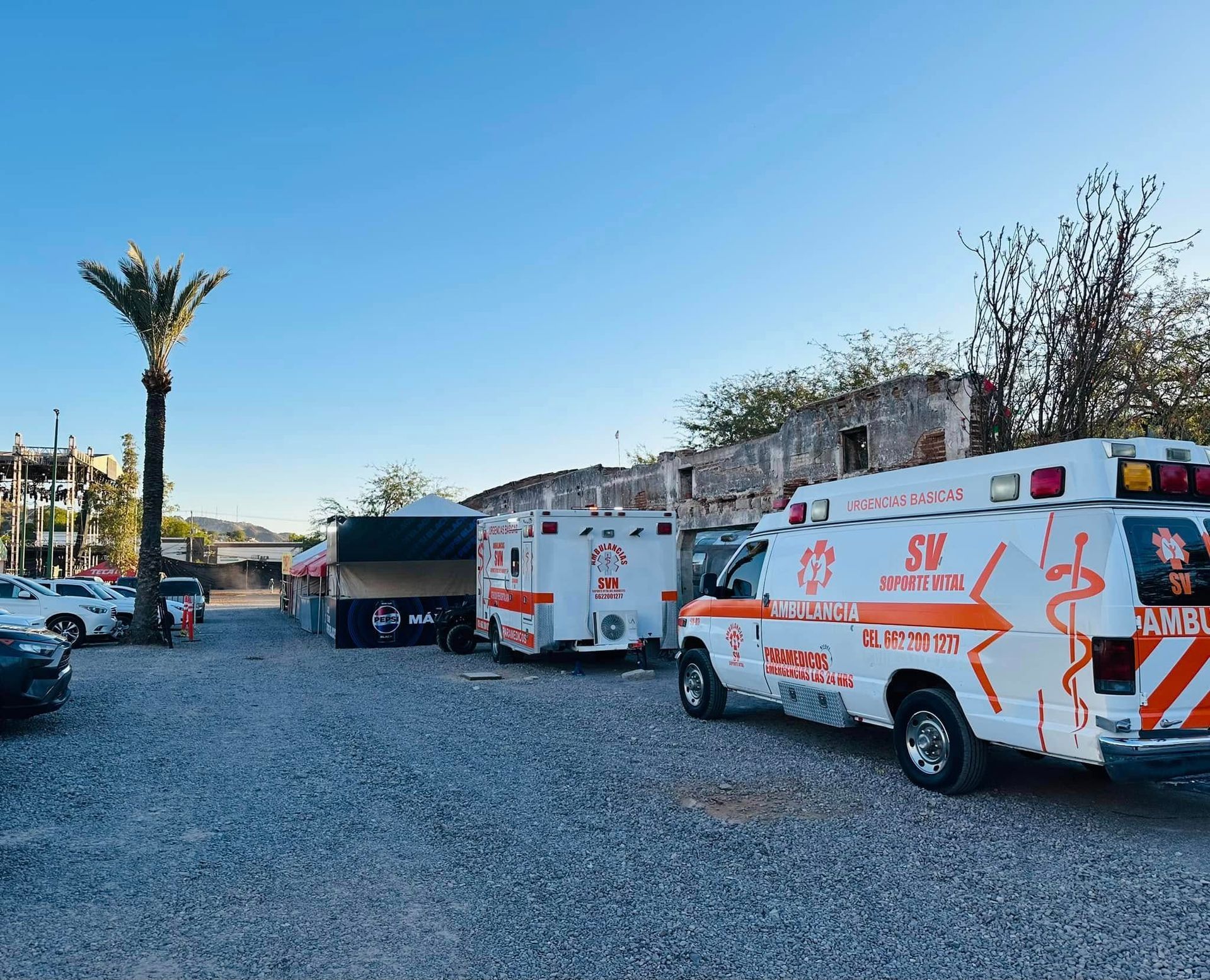 Una fila de ambulancias están estacionadas en un estacionamiento de grava.