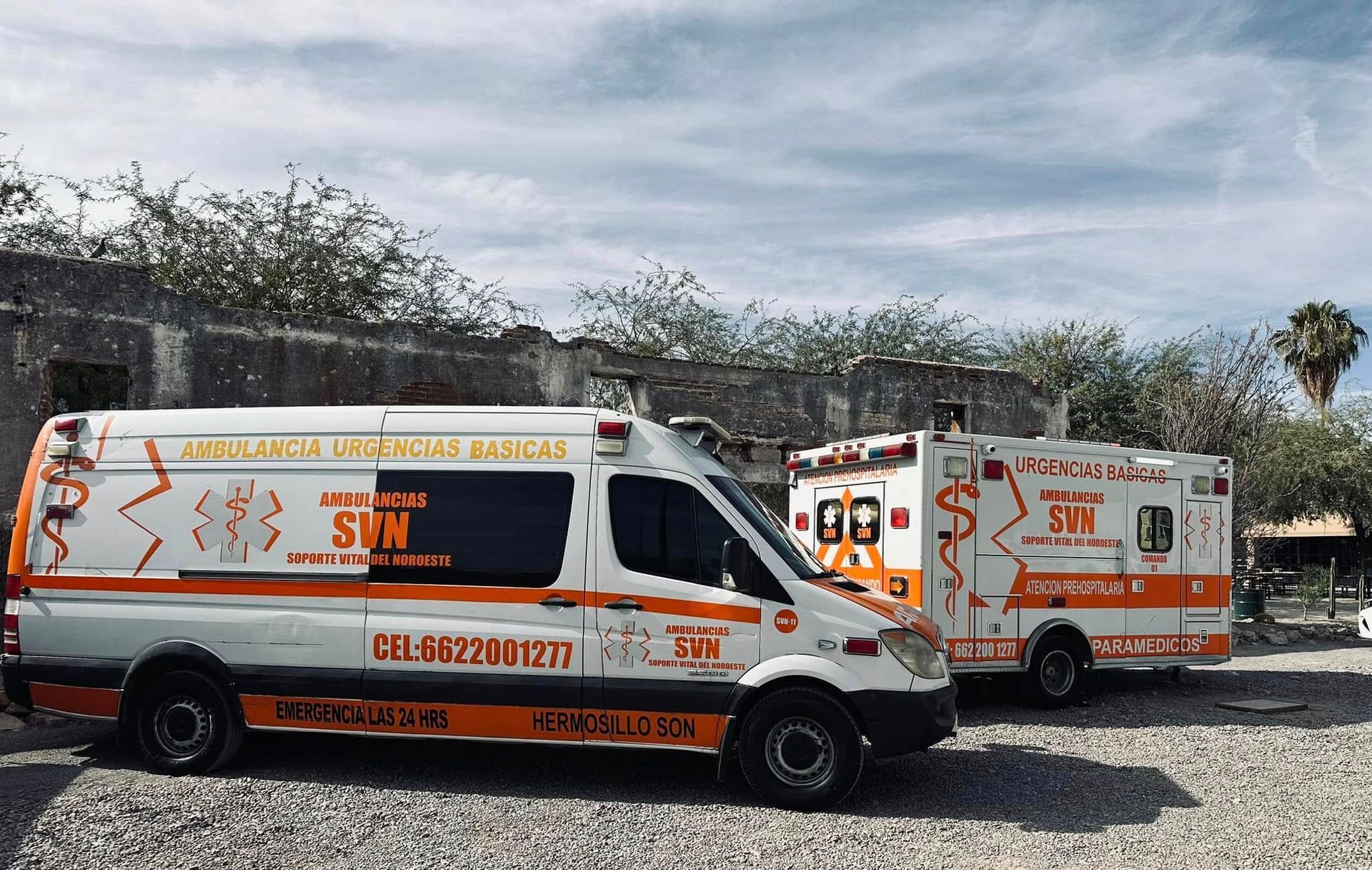 Dos ambulancias están estacionadas una al lado de la otra en un estacionamiento de grava.