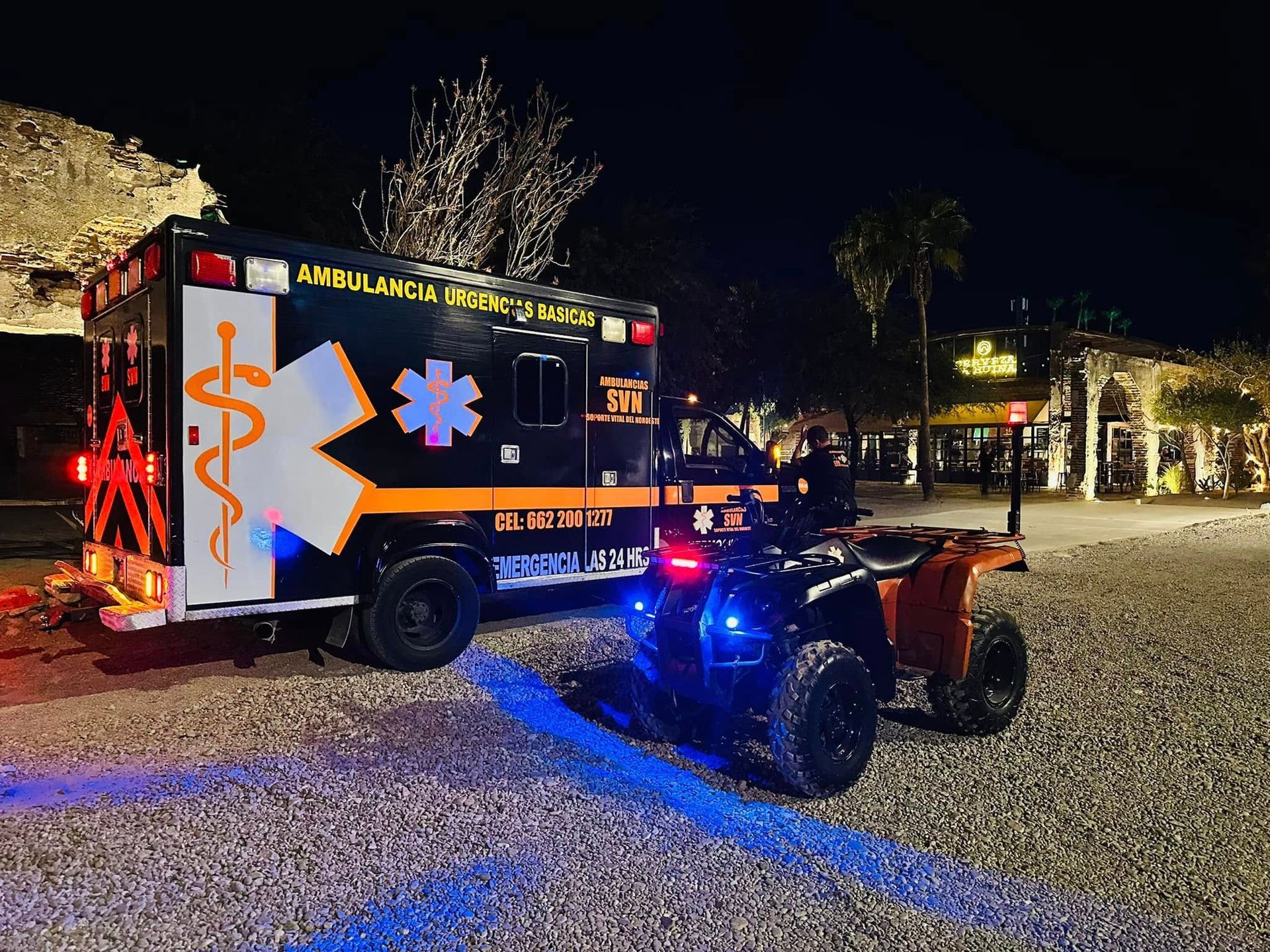 Una ambulancia y un vehículo todo terreno están estacionados en un estacionamiento por la noche.