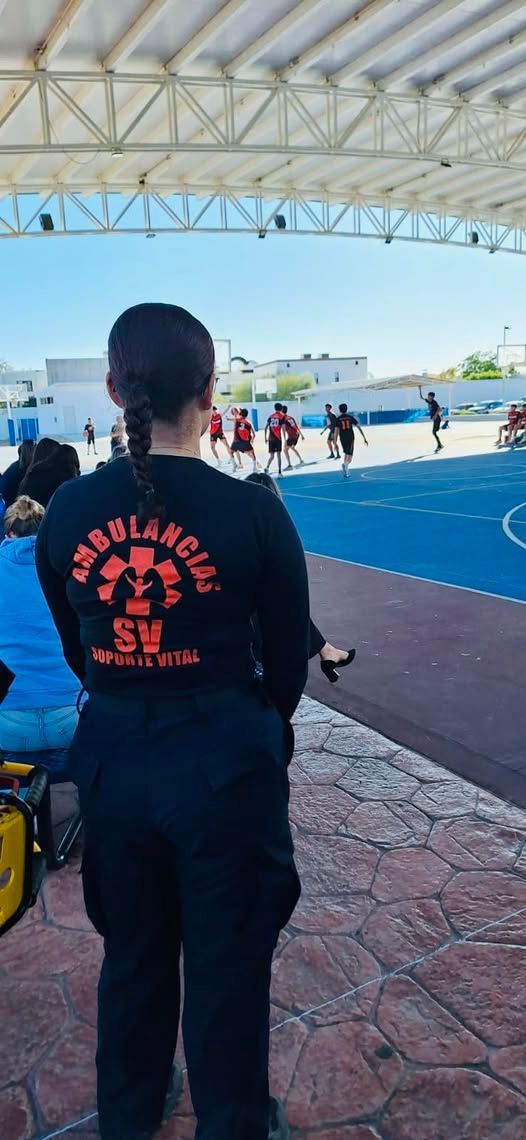 Una mujer está parada frente a una cancha de baloncesto viendo un partido.
