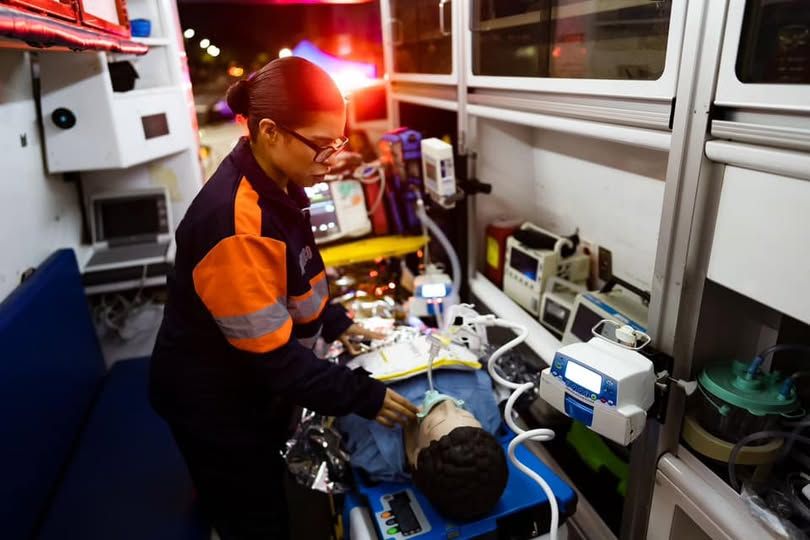 Una mujer está atendiendo a un paciente en una ambulancia.