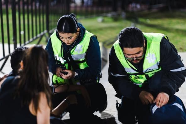Un grupo de paramédicos está ayudando a una mujer que se encuentra en el suelo.