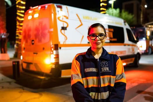 Una mujer está parada frente a una ambulancia por la noche.