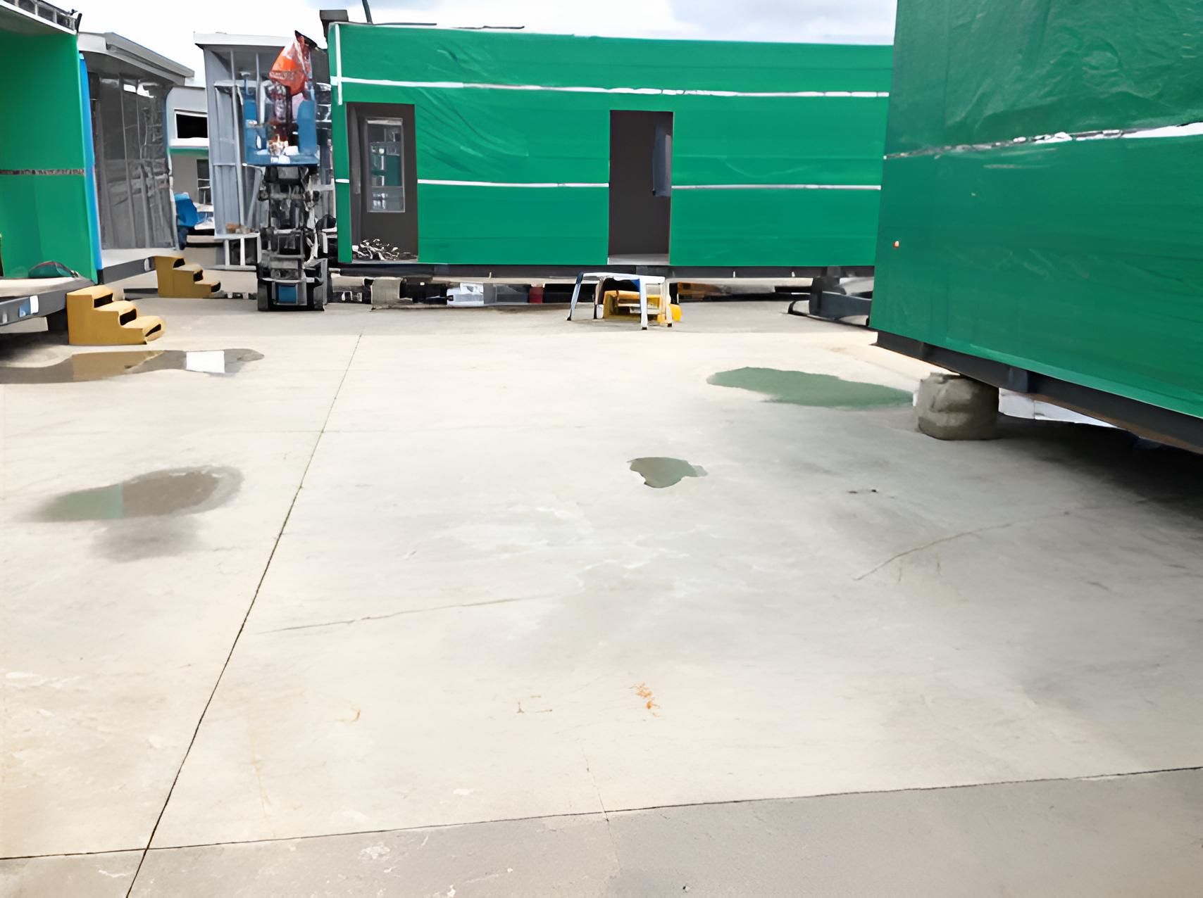 A Concrete Driveway With A Green Building In The Background — EcoPro Pressure Cleaning In Broadbeach Waters, QLD