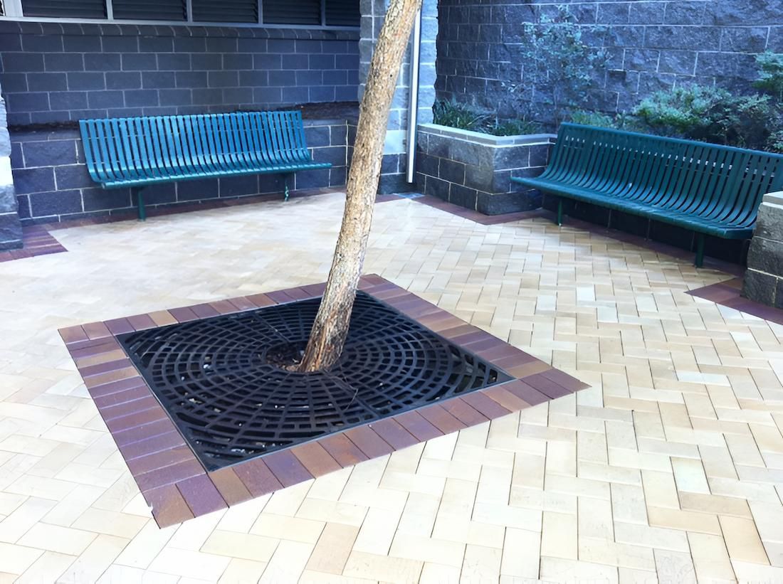 A Tree Is Surrounded By Bricks In A Courtyard With Two Benches — EcoPro Pressure Cleaning In Logan, QLD