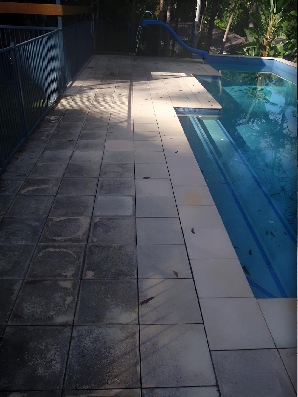 A Swimming Pool With A Slide In The Background — EcoPro Pressure Cleaning In Nerang, QLD